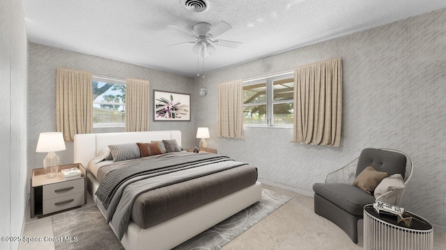 carpeted bedroom featuring a textured ceiling, multiple windows, and visible vents