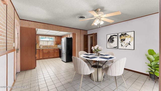 dining space featuring a textured ceiling, brick wall, light tile patterned floors, and visible vents