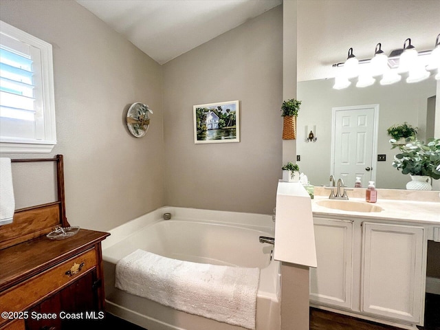 bathroom with vanity, vaulted ceiling, and a bathtub