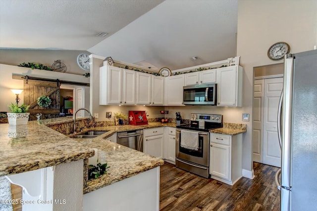 kitchen with stainless steel appliances, light stone countertops, a barn door, white cabinetry, and kitchen peninsula