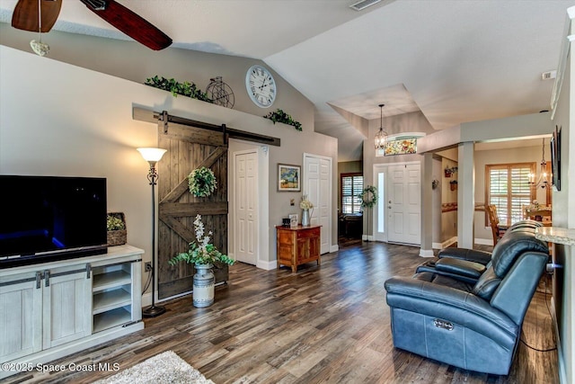 living room featuring ceiling fan, a barn door, dark wood-type flooring, and vaulted ceiling