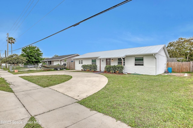 ranch-style home featuring stucco siding, concrete driveway, a front yard, fence, and metal roof