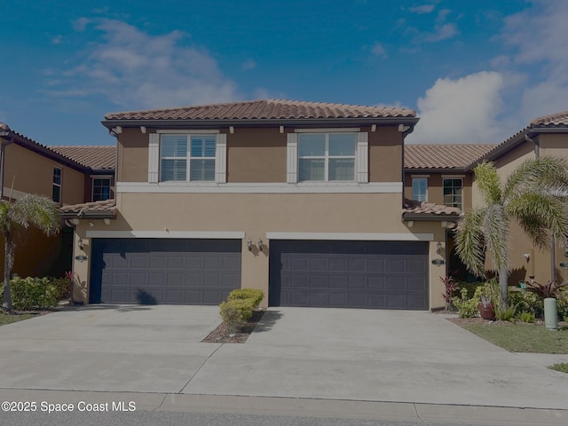 view of front of home featuring concrete driveway, an attached garage, a tile roof, and stucco siding