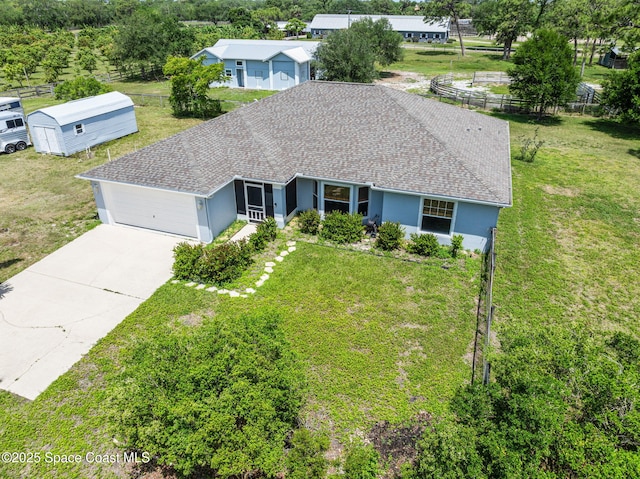 view of front of home with concrete driveway, a front lawn, fence, and a garage