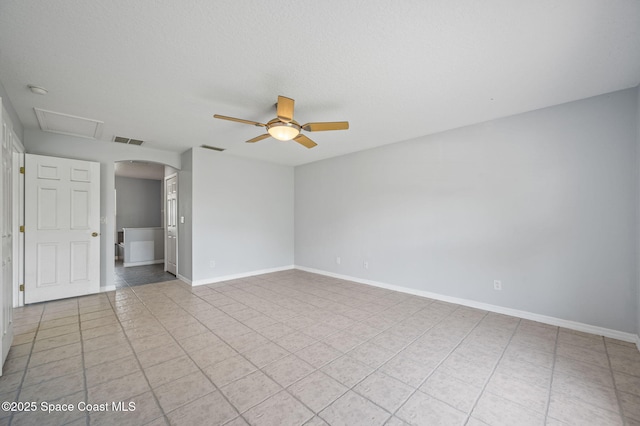 spare room featuring arched walkways, visible vents, a ceiling fan, and light tile patterned floors
