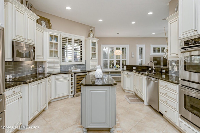 kitchen with stainless steel appliances, white cabinetry, sink, and kitchen peninsula