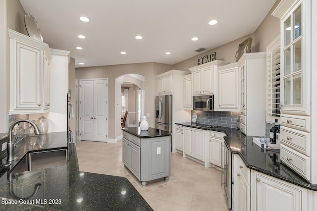 kitchen with stainless steel appliances, sink, white cabinets, and dark stone counters