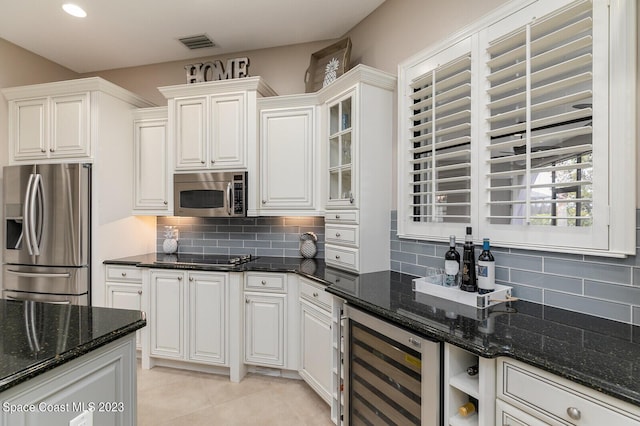 kitchen with wine cooler, white cabinetry, dark stone countertops, and appliances with stainless steel finishes