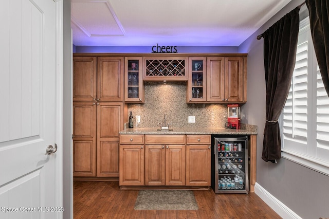 bar featuring light stone counters, dark hardwood / wood-style floors, beverage cooler, and decorative backsplash