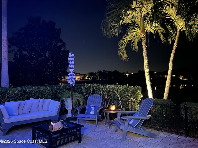 patio at night with an outdoor living space with a fire pit