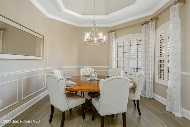 dining space with hardwood / wood-style flooring, crown molding, and an inviting chandelier