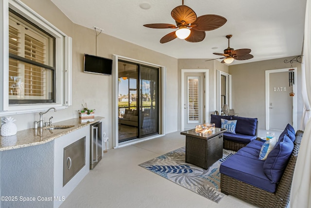 view of patio / terrace featuring wine cooler, ceiling fan, sink, and an outdoor living space with a fire pit