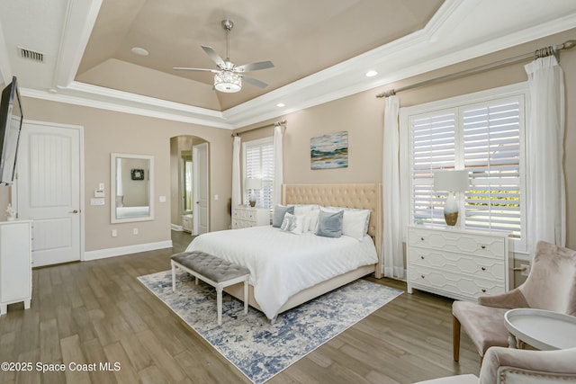 bedroom featuring crown molding, light hardwood / wood-style flooring, and a raised ceiling