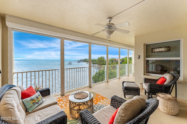 sunroom / solarium featuring ceiling fan and a water view