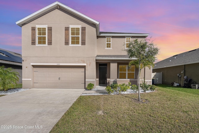 traditional-style home featuring a front yard, driveway, an attached garage, and stucco siding