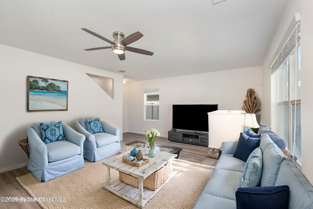 living room featuring baseboards, ceiling fan, and wood finished floors