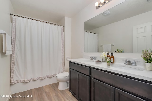 bathroom with double vanity, a sink, wood finished floors, and toilet