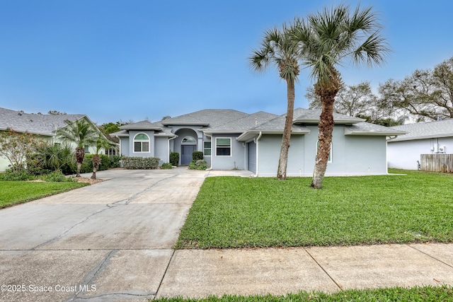 view of front of house with concrete driveway, a front lawn, and stucco siding