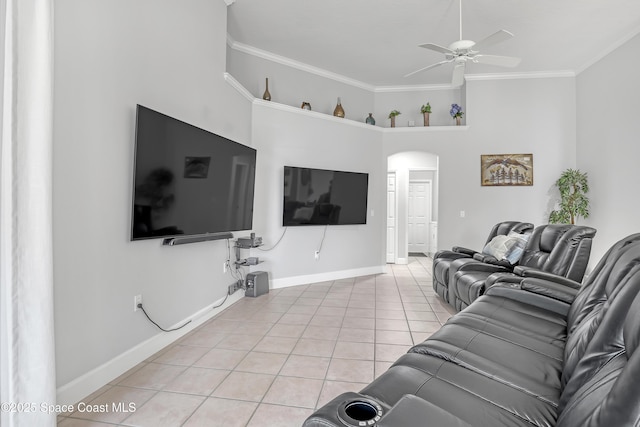 living area featuring arched walkways, ceiling fan, light tile patterned flooring, baseboards, and ornamental molding