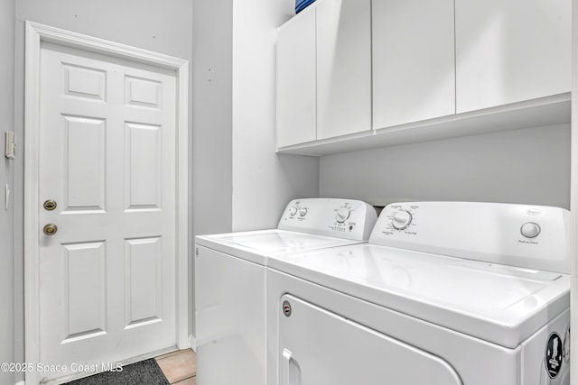 laundry area featuring washer and dryer, tile patterned flooring, and cabinet space