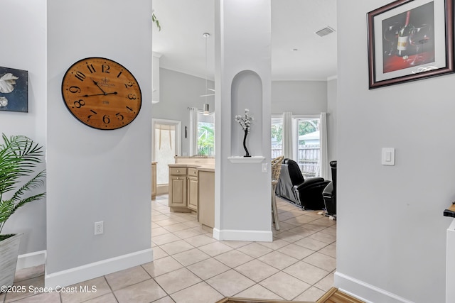 hallway with ornamental molding, baseboards, and light tile patterned floors