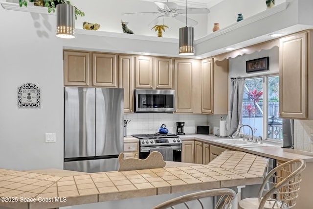 kitchen with light brown cabinets, stainless steel appliances, a sink, and decorative light fixtures