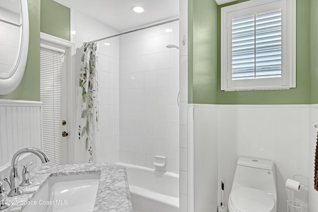 full bathroom with a wainscoted wall, shower / tub combo, vanity, and toilet