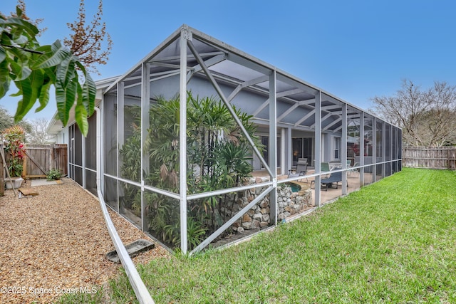 view of side of home featuring glass enclosure, a yard, a patio, and a fenced backyard