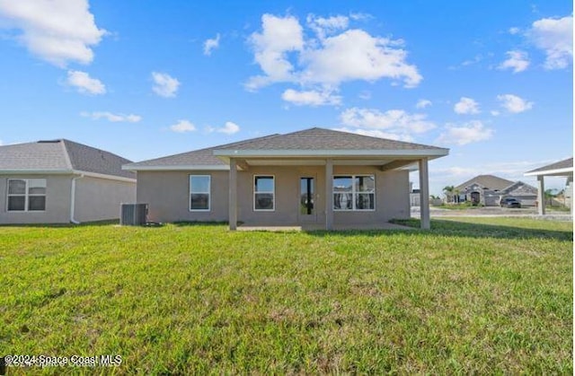 back of property with central AC and a lawn