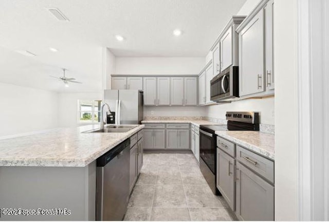 kitchen with sink, light stone counters, a center island with sink, light tile patterned floors, and appliances with stainless steel finishes