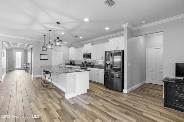 kitchen with stainless steel appliances, white cabinetry, a kitchen island with sink, and a kitchen breakfast bar