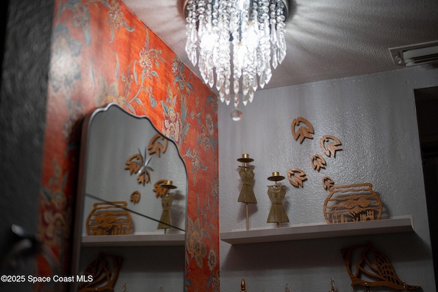 room details with a textured wall, a textured ceiling, and an inviting chandelier