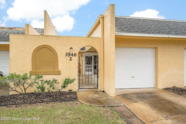 view of front of property featuring driveway, stucco siding, and roof with shingles