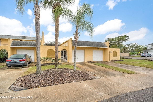 view of front of property featuring driveway, stucco siding, a garage, and roof with shingles