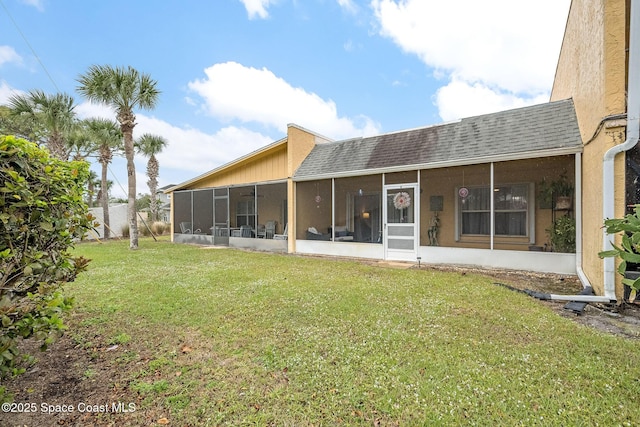 back of house featuring a sunroom, roof with shingles, and a yard