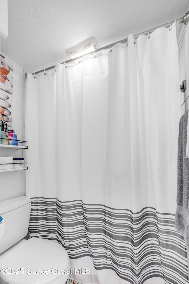 bathroom featuring a textured ceiling and toilet