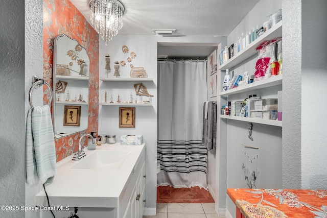 bathroom with a textured ceiling, a chandelier, vanity, visible vents, and tile patterned floors