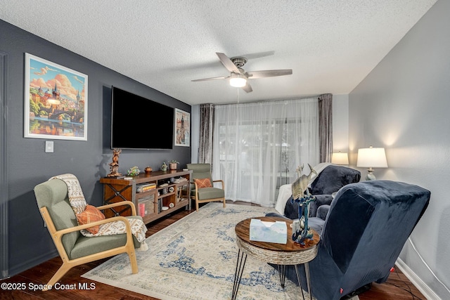 living room featuring ceiling fan, a textured ceiling, wood finished floors, and baseboards