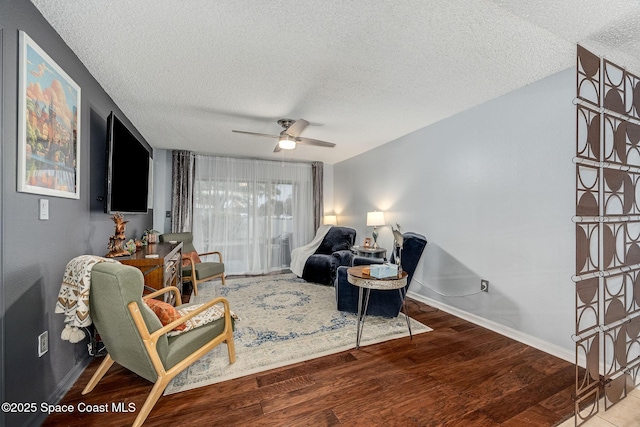 living area with a ceiling fan, a textured ceiling, baseboards, and wood finished floors