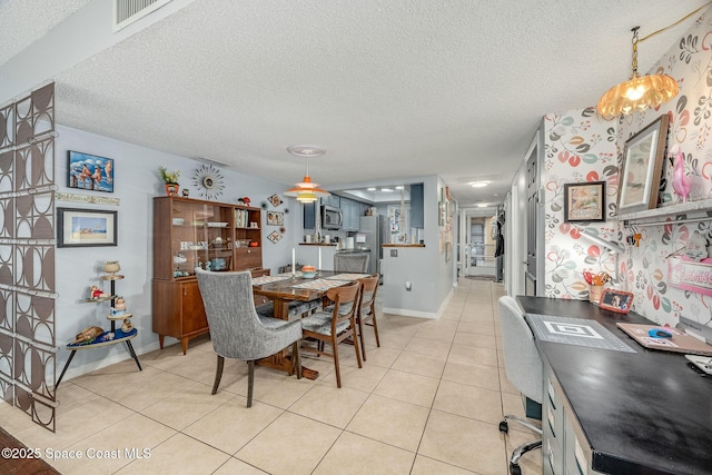 dining space with a textured ceiling, light tile patterned flooring, visible vents, and baseboards