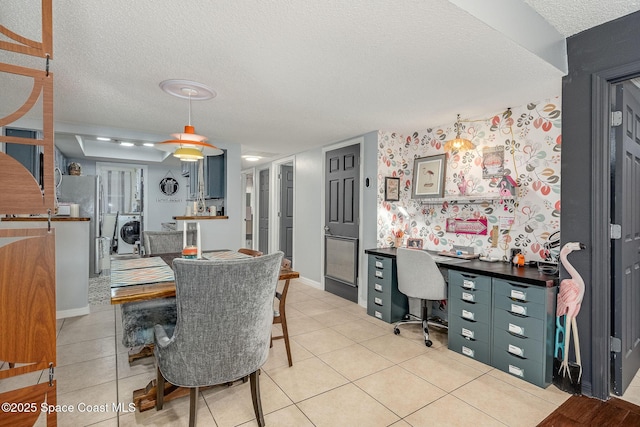 dining space featuring washer / clothes dryer, light tile patterned flooring, a textured ceiling, and baseboards