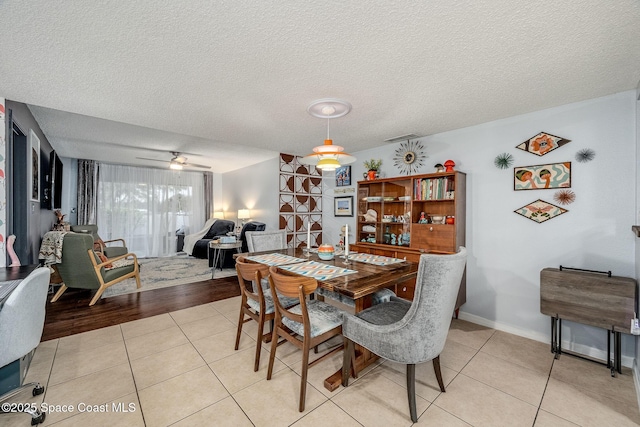 dining space featuring light tile patterned floors, ceiling fan, a textured ceiling, and baseboards