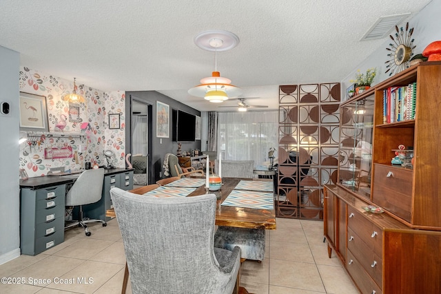 dining room with visible vents, light tile patterned flooring, ceiling fan, a textured ceiling, and wallpapered walls