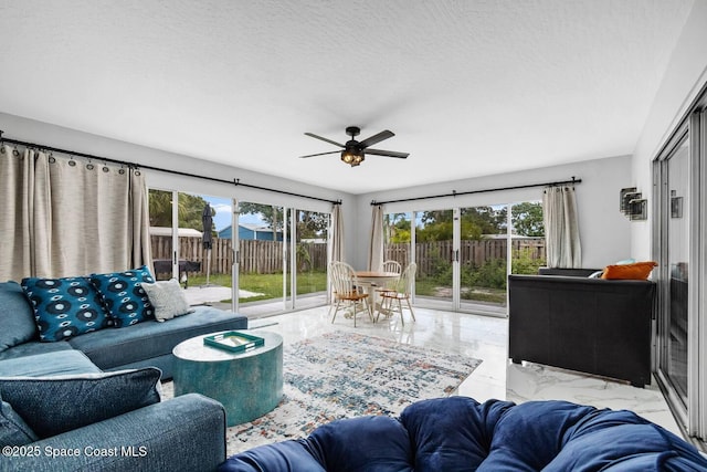 living room featuring ceiling fan and a textured ceiling