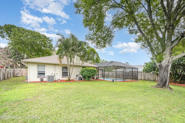 view of yard with glass enclosure, central air condition unit, a fenced in pool, and a fenced backyard