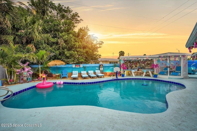 pool at dusk featuring a patio area