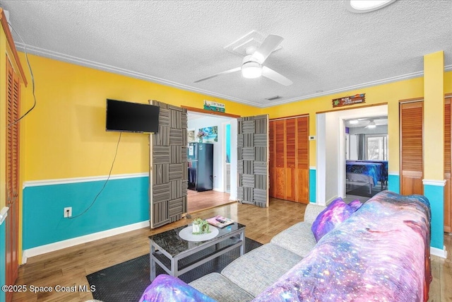 living room featuring hardwood / wood-style flooring, ceiling fan, and a textured ceiling