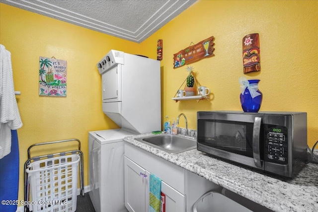 clothes washing area featuring stacked washer and dryer, sink, and a textured ceiling