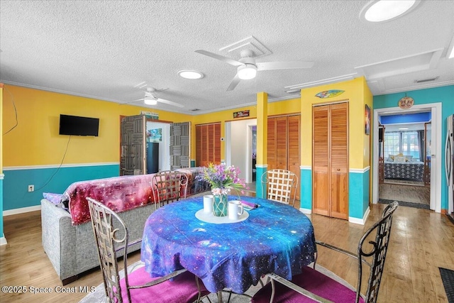 dining space featuring wood-type flooring, a textured ceiling, and ceiling fan