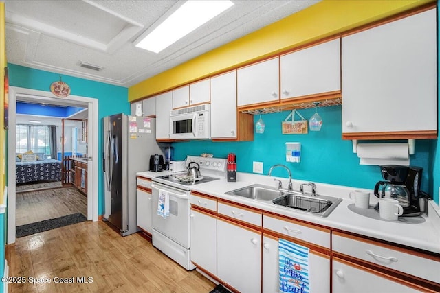 kitchen with sink, white cabinets, white appliances, and light wood-type flooring